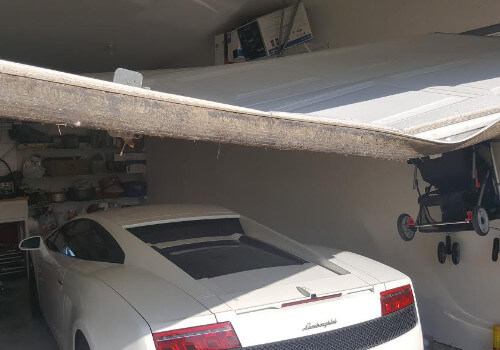 Lamborghini in garage with a broken garage door overhead