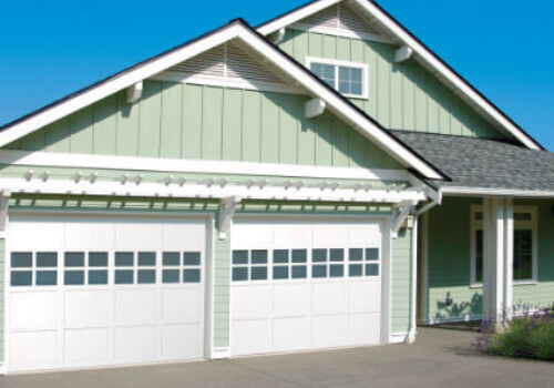 Pale mint green house with newly installed white overhead garage doors